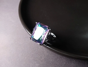 Macro shot of rectangular mystic topaz ring with black floral engraved band details