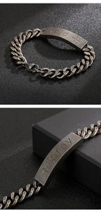 Detail of vintage steel Cuban chain bracelet with Pray engraving and cross on ID plate