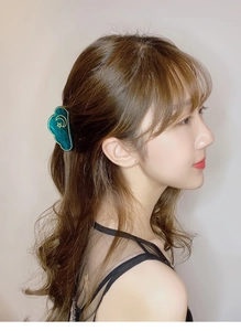 Detailed view of a green cloud hair claw with gold moon pattern worn by a model