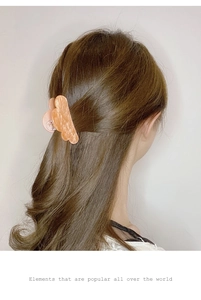 Close-up of star-patterned acrylic hair claw clip worn by a model in a ponytail