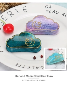 Detailed shot of marbled acrylic star and moon cloud hair claw clips on a ceramic dish
