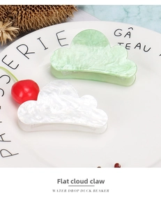 Detail of light green and white cloud-shaped hair claws on a decorative white porcelain plate