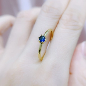 Classic six-prong round blue zircon ring with slender gold plated band on finger