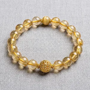 Detail of yellow crystal beaded bracelet with gold hollow charm on wrist