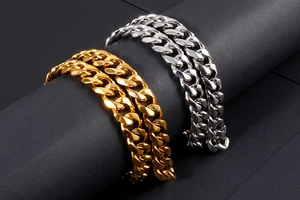 Dettaglio dei bracciali a maglia cubana in oro e argento su un supporto nero elegante