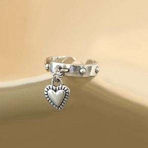 Detail of silver open ring featuring a heart tag charm and stud texture accents