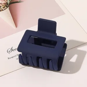 Detail of a large matte navy blue rectangular hair claw clip with a strong spring