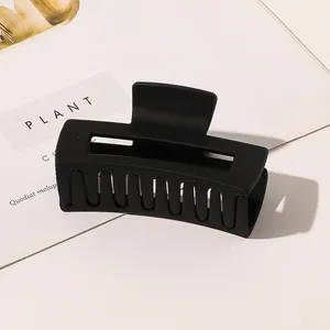Detail of large matte black rectangular hair claw clip with minimalist hollow design