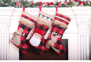 Three red and black buffalo plaid Christmas stockings hanging on a white festive fireplace