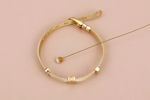 Detail eines Gold-Mesh-Armbands aus Edelstahl mit verstellbarem Verschluss und Anhänger