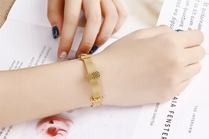 Details von Gold-Ananas und Love-Anhängern an einem Edelstahl-Mesh-Armband