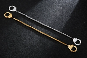 Detail of gold and silver handcuff charm bracelets with sleek metal beaded chains