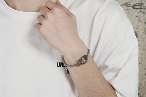 Detailed shot of stainless steel bead chain bracelet with silver handcuff clasp on wrist