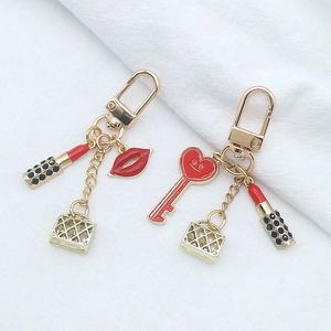 Detail of creative lipstick and red lip charms on gold-finished metal keychain sets