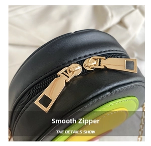Detail of smooth gold dual metal zippers on a round faux leather crossbody bag