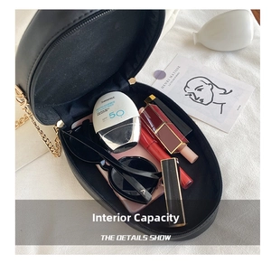 Detail view of round black PU leather bag interior showing daily essentials and gold zipper