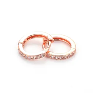 Close-up of rose gold huggie hoop earrings with micro-paved white cubic zirconia stones