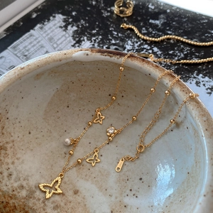 Close-up of 925 silver butterfly necklace with small pearls on a rustic ceramic bowl