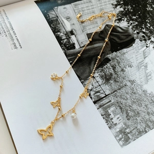 Detail of 925 silver golden necklace with butterfly charm, pearl, and zircon accent