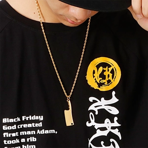 Golden mini cleaver pendant necklace with twist chain on model wearing black t-shirt