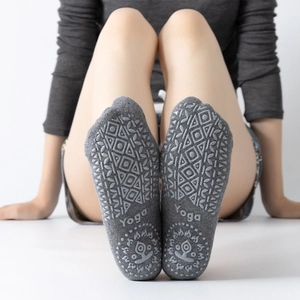 Grey knit yoga socks with anti-slip silicone grip dots and lotus logo on white background
