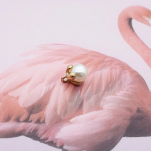 Detailed view of a white pearl pendant encased in a delicate golden leaf metal setting
