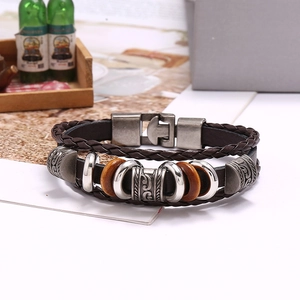 Detail of vintage multilayer brown braided leather bracelet with carved metal and wood beads