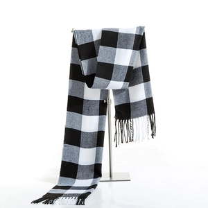 Classic black and white checkered scarf with fringe hanging on a metal display stand