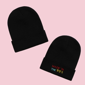 Classic black knitted beanie with 'MADE IN THE 90'S' embroidery on a pink background