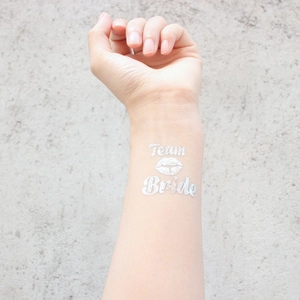 Close-up of Team Bride silver glitter temporary tattoo with lip design on forearm