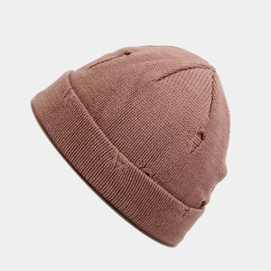 Detail of distressed ripped knit beanie hat in dusty rose color with rolled cuff design