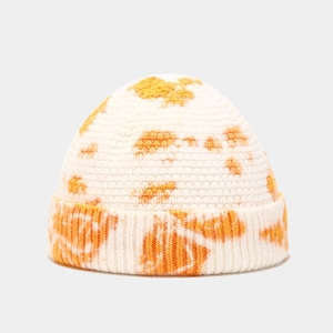 Close-up of knit texture on cream and orange tie-dye skull cap for winter warmth