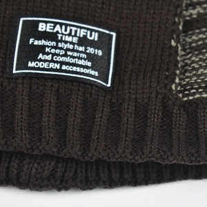 Vista macro dettagliata del berretto in maglia marrone scuro con etichetta logo in tessuto