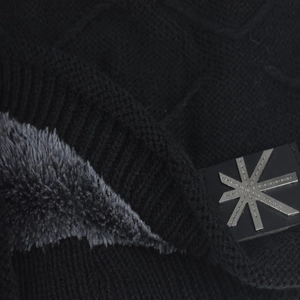 Macro shot of black winter knit hat featuring thick grey fleece lining and metal star detail