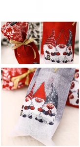 Close-up of burlap Christmas wine bottle bags with gnome prints and gold ribbons
