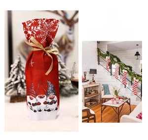 Close-up of red burlap Christmas wine bottle bag with gnomes and golden ribbon