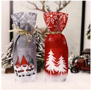 Detail of Christmas wine bottle covers with red tree and grey gnome on linen texture