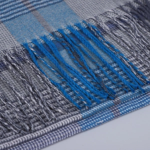 Vue macro des franges délicates et du motif à carreaux bleu-gris sur cette écharpe d'hiver