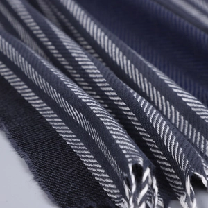 Vue macro du tissage à chevrons bleus et des franges douces d'une écharpe d'hiver pour homme