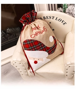 Detail of burlap Christmas gift bag with Santa Claus embroidery and red drawstring