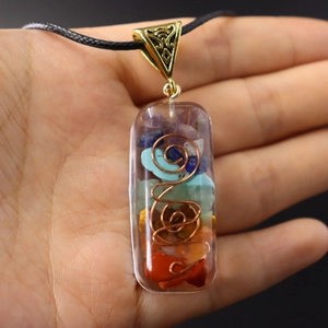 Chakra stone pendant with natural crystals and copper wire coil held in hand