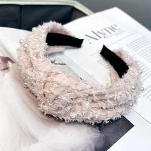 Close-up of pink knit headband with pearls on a magazine for elegant hair styling