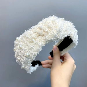 Detailed shot of beige tweed headband featuring elegant faux pearls and a soft knot design