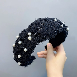 Detailed view of wide black feathered yarn headband decorated with elegant white pearls