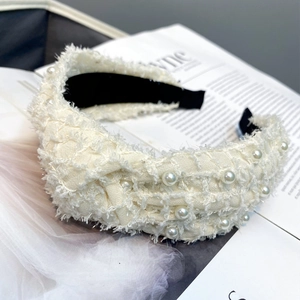 Detail of cream white tweed wide headband with pearl embellishments and knotted design