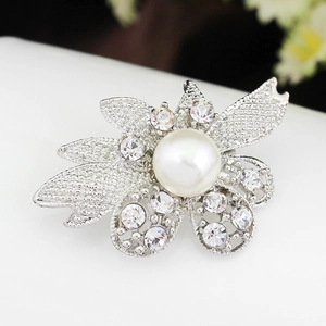 Macro detail of silver flower brooch featuring central pearl and sparkling crystal petals