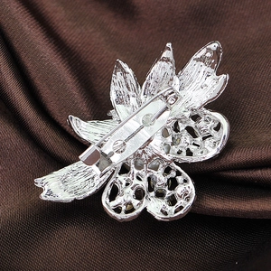 Macro shot showing the silver flower brooch back and safety pin on brown silk fabric