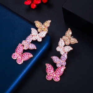 Close-up of rose gold butterfly earrings with colorful zircon stones on dark base