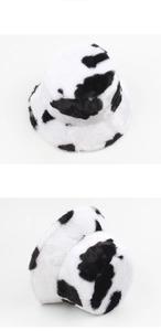 Détail montrant la texture en peluche et le motif de vache noir et blanc du bob d'hiver