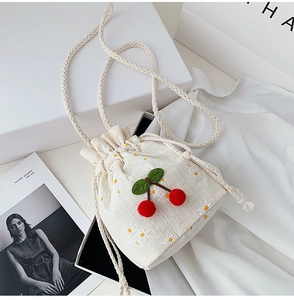 Detail of canvas drawstring bucket bag with cherry patch and floral embroidery